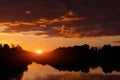 Sunset, sunrise on storm sky with dark clouds, orange yellow red sun and sunlight in reflection of river, lake water Royalty Free Stock Photo