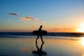 Sunset surfing. Silhouette of man surfer walking with a surf board in his hands across the ocean shore. Royalty Free Stock Photo