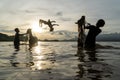 At sunset, three silhouettes of people cleaning racehorses on a beach in Lariti Beach, Bima district, West Nusa Tenggara. Bathing