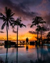 sunset tropical pool with palm trees, couple man and woman watching sunset by the pool with palm trees during vacation Royalty Free Stock Photo