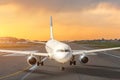 Sunset view of airplane on airport runway after landing taxiing under dramatic sky