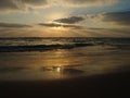 Sunset view on a calm sandy beach with cloudy sky and golden light