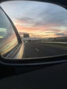 sunset view with clouds in car rearview mirror. Royalty Free Stock Photo