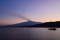 A sunset view of Etna volcano mountain and a boat silhouette on the sea. Royalty Free Stock Photo