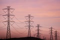 Sunset view of high voltage electricity towers on the hills of San Francisco bay area; Wind turbines visible in the background; Royalty Free Stock Photo