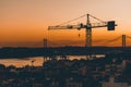 Sunset view of Lisbon with crane and rope bridge Royalty Free Stock Photo