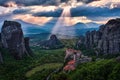 Sunset view of nunnery of Moni Agias Varvaras Roussanou and rocks of Meteora, Greece and valley. Cloudy sky, sun rays Royalty Free Stock Photo