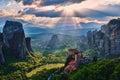 Sunset view of nunnery of Moni Agias Varvaras Roussanou and rocks of Meteora, Greece and valley. Cloudy sky, sun rays Royalty Free Stock Photo