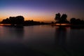 Sunset view over Love lake in the Al Qudra desert, tree silhouettes, purple and blue sky background