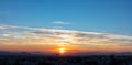 Sunset view from Penteli, Athens, Greece. Sun falling over mountains, blue sky with clouds background Royalty Free Stock Photo