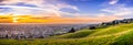 Sunset view of residential and industrial areas in East San Francisco Bay Area; green hills visible in the foreground; Hayward,