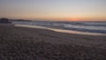 Sunset view of sand beach Praia Grande de Almograve with ocean waves in pink and red blue hour light, clear blue sky Royalty Free Stock Photo