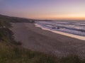 Sunset view of sand beach Praia Grande de Almograve with ocean waves in pink and red blue hour light, clear sky. Rota Royalty Free Stock Photo