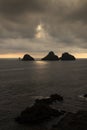 Sunset view of small rocky islands in the ocean and sun breaking through clouds. Heimaey Island, Vestmannaeyjar, Iceland