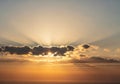 The sun partially obscured by horizontal clouds, casting dramatic rays Royalty Free Stock Photo