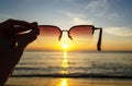 Sunset view through sunglasses in hand, Sunset over the sea, natural background, space for text. Royalty Free Stock Photo