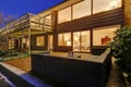 Sunset view of two story home with upper deck and lower poolside patio