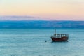 Sunset view of a wooden boat floating on the sea of galilee, Israel