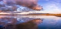 Sunset views of the restored wetlands of South San Francisco Bay Area, with dark clouds reflected on the water surface and Diablo