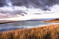 Sunset views of the restored wetlands of South San Francisco Bay Area, with dark clouds reflected on the water surface and Diablo