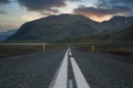 Sunset and vivid colors over big mountain scenery at the end of a long road. Royalty Free Stock Photo