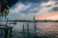 Sunset at Wat Arun. Chao Phraya with Longboat at Sunset. View from a Restaurant with some tourists inside.