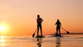 Sunset waters with a boy and a mother doing paddlesurfing