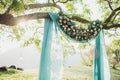 Sunset wedding ceremony arch with flower decoration and blue cloth hang on tree Royalty Free Stock Photo