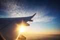 Sunset and wing of an airplane flying above the Earth. The view from an airplane window Royalty Free Stock Photo