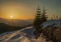 Sunset in the winter Carpathian mountains. Sun disk and long rays at sunset in the winter mountains. Picturesque sunset in the mou