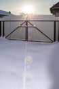 Sunset in the winter. Sunbeams in the snow. Garage metal gates covered with snow