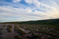 Sunset with yellow sun and white clouds on blue sky over the steppe with hills Royalty Free Stock Photo