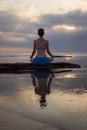 Sunset yoga. Caucasian woman sitting on the stone in Lotus pose. Padmasana. Hands in gyan mudra. Beach in Bali. View from back. Royalty Free Stock Photo