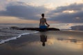 Sunset yoga. Caucasian woman sitting on the stone in Lotus pose. Padmasana. Hands in gyan mudra. Beach in Bali. View from back. Royalty Free Stock Photo