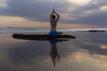 Sunset yoga. Caucasian woman sitting on the stone in Lotus pose. Padmasana. Hands in namaste mudra. Bali beach. View from back. Royalty Free Stock Photo