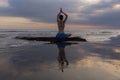 Sunset yoga. Caucasian woman sitting on the stone in Lotus pose. Padmasana. Hands in namaste mudra. Bali beach. View from back. Royalty Free Stock Photo