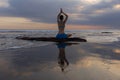 Sunset yoga. Caucasian woman sitting on the stone in Lotus pose. Padmasana. Hands in namaste mudra. Bali beach. View from back. Royalty Free Stock Photo