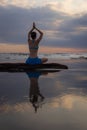 Sunset yoga. Caucasian woman sitting on the stone in Lotus pose. Padmasana. Hands in namaste mudra. Bali beach. View from back. Royalty Free Stock Photo