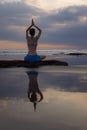 Sunset yoga. Caucasian woman sitting on the stone in Lotus pose. Padmasana. Hands in namaste mudra. Bali beach. View from back. Royalty Free Stock Photo