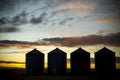 Sunsetting behind four silos Royalty Free Stock Photo