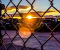 Sunsetting behind parked trucks in parking lot, through a chain link fence. Royalty Free Stock Photo