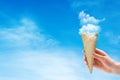 Woman hand holding Ice cream cone with white cloud with blue sky in background. Royalty Free Stock Photo