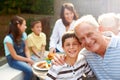 Sunshine and love at a Sunday lunch. Portrait of a grandfather and grandson embracing at a family lunch outdoors - Royalty Free Stock Photo