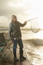 Sunshine, net and beach with man, fish and hobby with equipment, waves and weekend break. Person, ocean and guy with Royalty Free Stock Photo