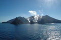 Sunshine on the sea surrounding a smoking volcano.