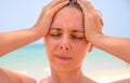 Sunstroke woman on tropical beach. Woman on hot beach with sunstroke. Headache from sun.