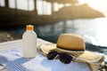Suntan cream bottle and sunglasses on beach towel with sea shore on background. Sunscreen on deck chair outdoors on Royalty Free Stock Photo