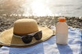 Suntan cream bottle and sunglasses on beach towel with sea shore on background. Sunscreen on deck chair outdoors on Royalty Free Stock Photo