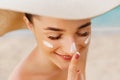 Suntan lotion woman applying sunscreen solar cream. Beautiful happy cute woman applying suntan cream to her nose Royalty Free Stock Photo