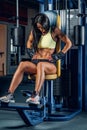 Suntanned fitness female exercising in a gym.